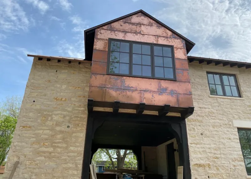 Copper metal panel facade on a stone building for Roof Repair in Muscatine